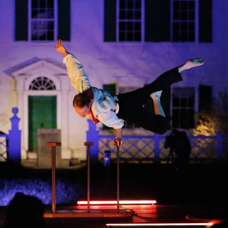 Performer balancing on one hand during a circus act at Old Sturbridge Village’s Phantoms by Firelight event.