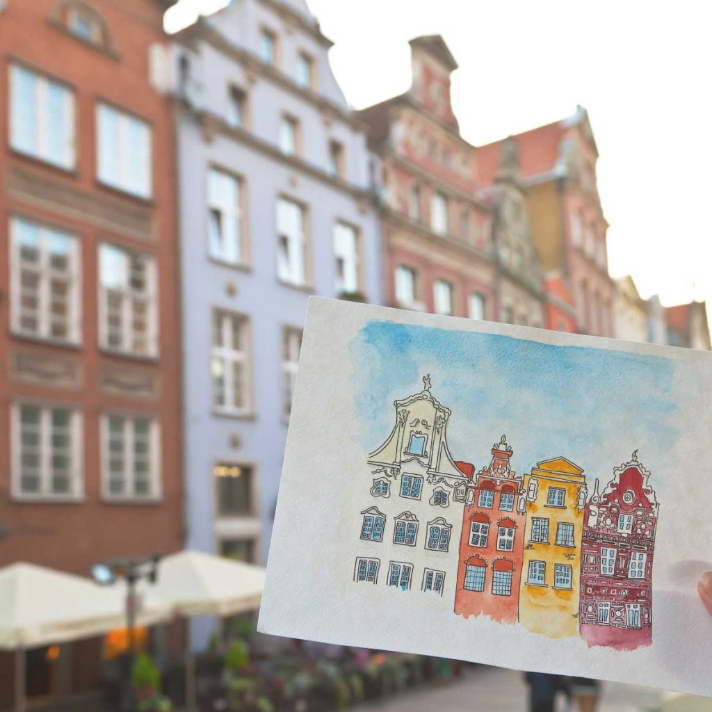 Watercolor sketch of historic European-style buildings held up against a real city street scene.